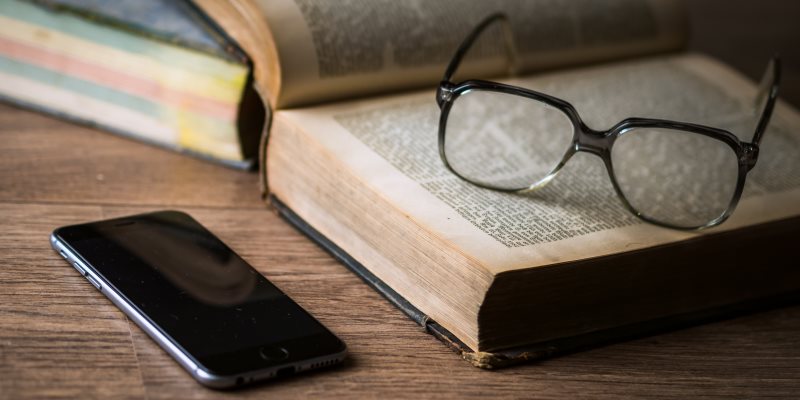 Livro, óculos e iPhone