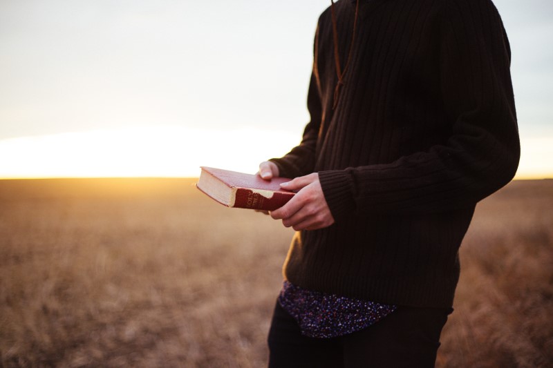 Homem no campo com a bíblia na mão