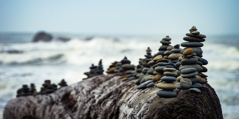 Versículos sobre paciência (imagem representando paciência - empilhamento de pequenas rochas em frente ao mar)