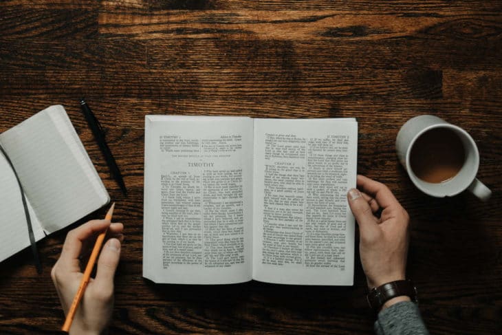 Bíblia, caderno de anotações e caneca de café sobre a mesa